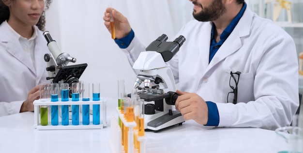 Chercheurs scientifiques travaillant en laboratoire de liquide jaune dans un tube à essai avec microscope