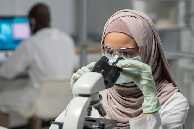 Chercheuse contemporaine en hijab regardant au microscope