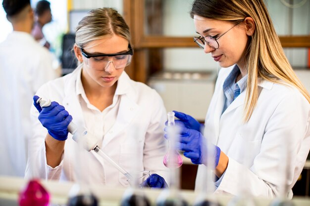 Chercheuses mignonnes en blouse blanche travaillant en laboratoire