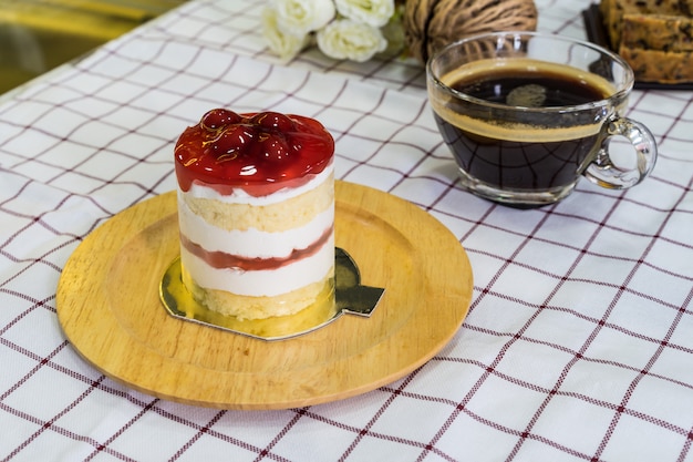 Cherry Cream Cake sur une assiette en bois et une tasse à café