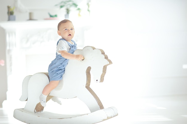 cheval à bascule enfant / petit garçon chevauchant un cheval jouet, fauteuil à bascule jouet enfant vintage