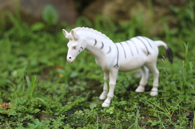 Cheval blanc ou jouet animal zèbre avec des points noirs sur un sol herbeux