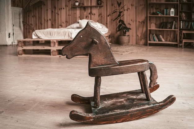 Photo cheval jouet en bois antique sur le sol de la chambre spacieuse. concept de souvenirs d'enfance heureux.