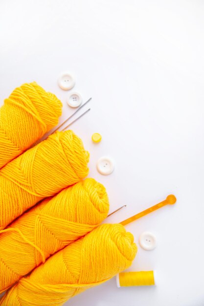 Écheveaux de boutons d'aiguilles à tricoter de fil jaune sur fond blanc