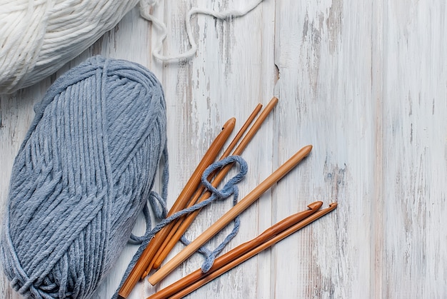 Écheveaux de fil et crochets pour tricoter sur une table en bois.