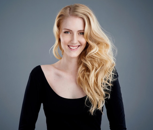 Des cheveux aussi lumineux que le soleil Portrait en studio d'une jolie jeune femme avec de beaux longs cheveux blonds posant sur un fond gris