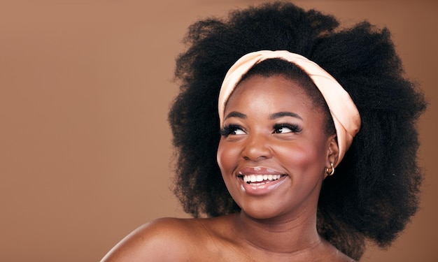 Cheveux de beauté et idée avec une femme noire modèle en studio sur fond marron pour les cosmétiques naturels Sourire du visage et soins capillaires avec une jeune femme afro heureuse pensant au traitement au shampoing