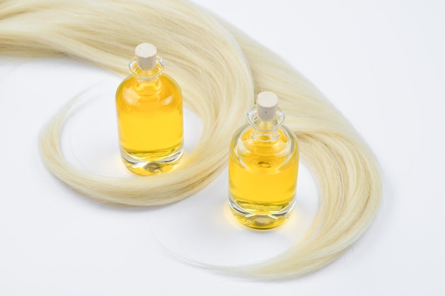 Cheveux blonds et bouteilles d'huile isolés sur fond blanc