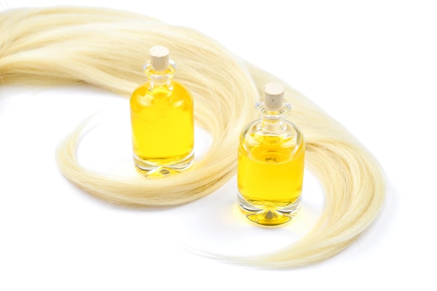 Cheveux blonds et bouteilles d'huile isolés sur fond blanc