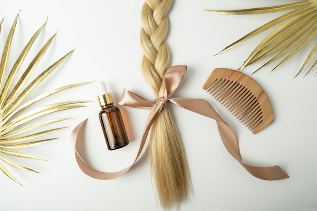 Cheveux blonds naturels et huile essentielle pour le traitement des cheveux se trouvant sur un fond blanc