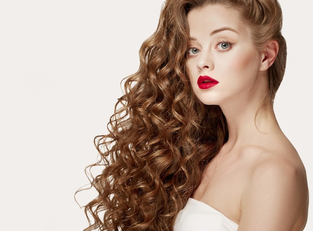 Cheveux bouclés portrait de femme cheveux longs avec un maquillage parfait des lèvres rouges isolées sur blanc