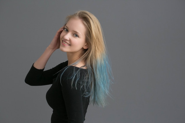 Cheveux de couleur femme avec une coiffure de couleur bleue sur un mur gris. Prise de vue en studio.