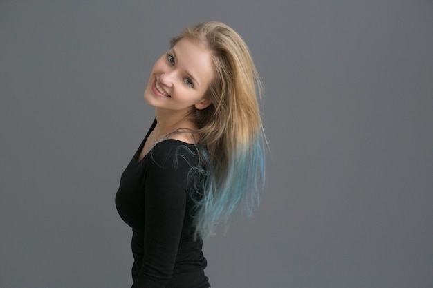 Cheveux de couleur femme avec une coiffure de couleur bleue sur un mur gris. Prise de vue en studio.