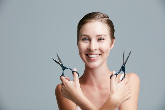 Les cheveux courts ne sont pas seulement pour les gars Portrait en studio d'une jolie jeune femme tenant des ciseaux sur un fond gris