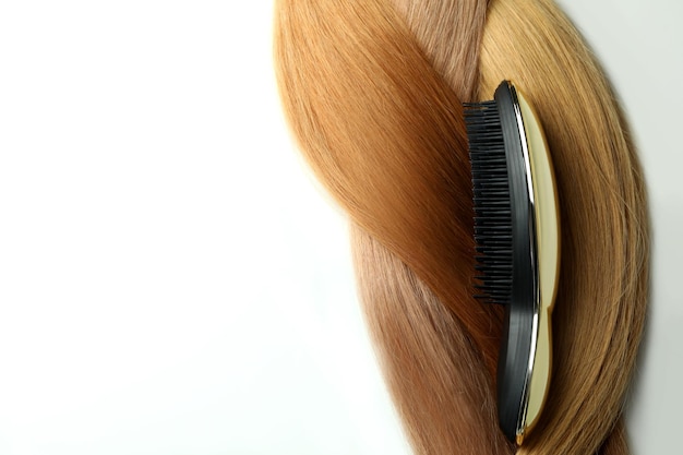 Cheveux féminins avec brosse à cheveux sur fond blanc