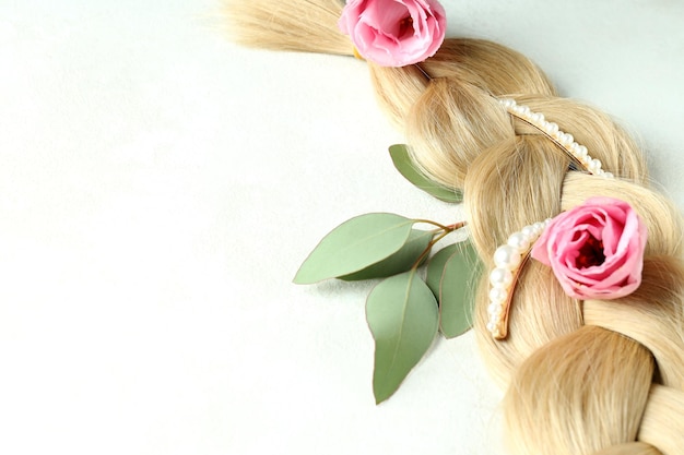 Cheveux féminins avec des fleurs et des pinces à cheveux sur fond clair