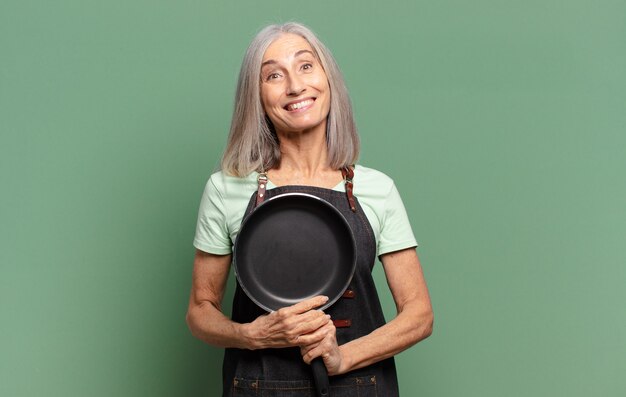 Cheveux gris jolie femme de chef d'âge moyen avec une casserole