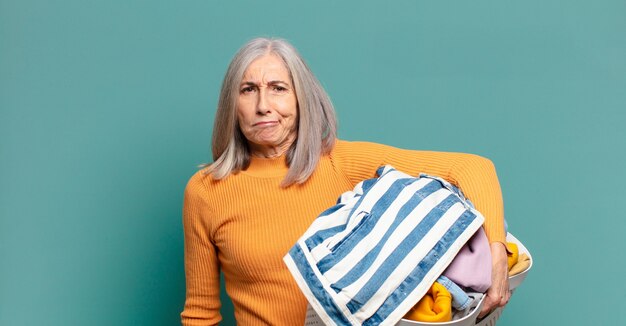 Cheveux gris jolie femme de ménage laver les vêtements