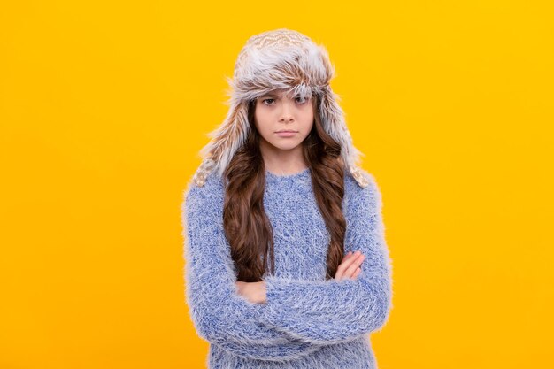 Cheveux longs enfant sérieux en chapeau sur la mode de saison de fond jaune