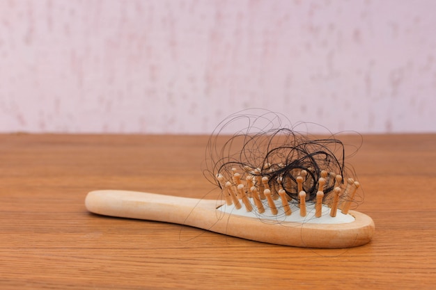 Cheveux tombés sur un peigne sur une table en bois