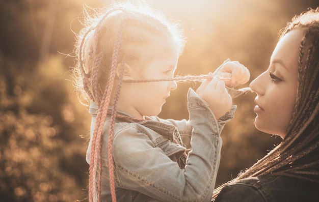 Photo cheveux en tresse de tissage à la mode heureuse famille aimante mère et fille tressage de cheveux belle enfant fille avec des tresses