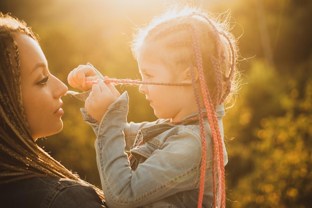 Cheveux en tresse de tissage à la mode, mère et fille de famille aimante heureuse tressant les cheveux belle fille d'enfant avec ...