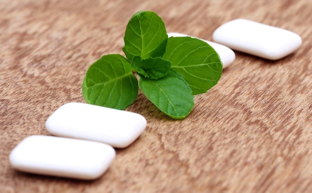 Chewing-gum avec des feuilles de menthe sur une surface en bois