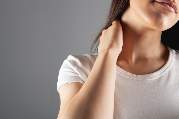 Chez une jeune femme, l'arrière de la tête fait mal sur fond gris