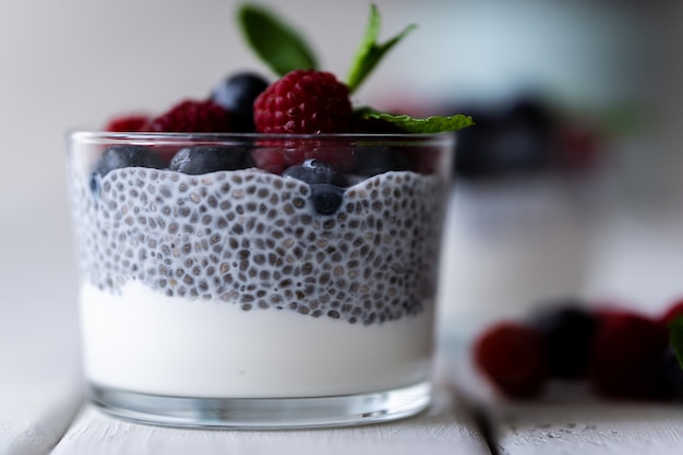 Chia aux baies sauvages. Framboises et myrtilles. Dessert délicieux et sain sur une table rustique en bois blanc.