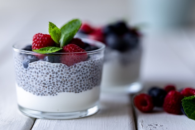 Chia aux baies sauvages. Framboises et myrtilles. Dessert délicieux et sain sur une table rustique en bois blanc.