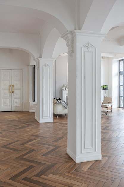 un chic intérieur lumineux coûteux d'un énorme salon dans un manoir historique avec des arches voûtées, des colonnes et des murs blancs décorés d'ornements et de stuc