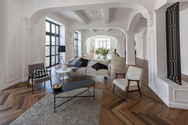 un chic intérieur lumineux coûteux d'un énorme salon dans un manoir historique avec des arches voûtées, des colonnes et des murs blancs décorés d'ornements et de stuc