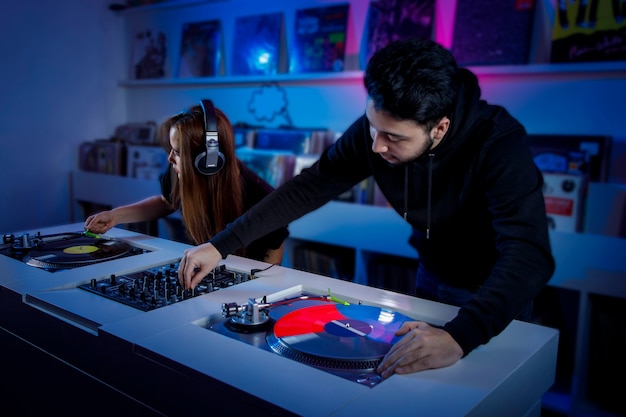 Photo chica y chico dj mezclando msica en una tienda de discos de vinilo usando un tornamesa retro