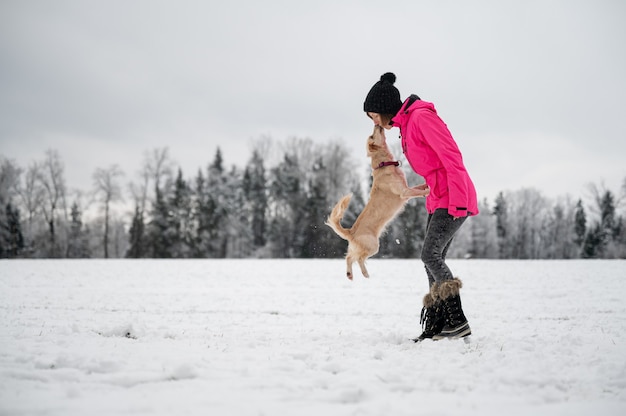 Chien de compagnie mignon sautant pour donner à son propriétaire un baiser à l'extérieur dans une belle nature enneigée.