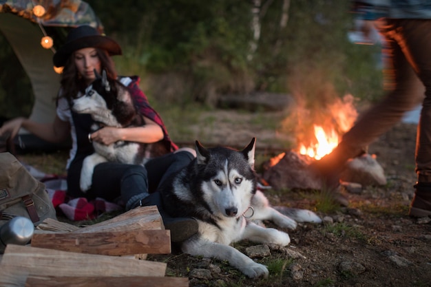 Chien est assis près du feu avec les hôtes et Husky