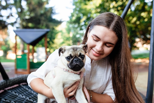 Chien et fille heureux La fille joue avec un chien Jeune femme marchant avec un chien carlin dans le parc d'été Portrait d'un carlin Portrait d'un beau chiot carlin Le chien est allongé sur le sol