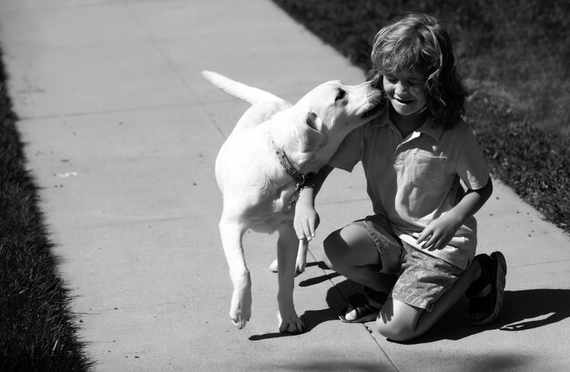 Un chien léche un enfant, un jeune garçon et un chien dans le parc. Un garçon heureux étreignant son animal de compagnie.