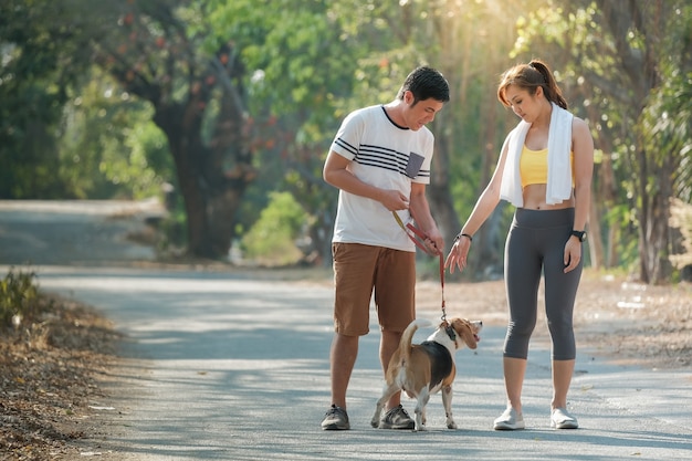 Le chien et le propriétaire ont passé une journée au parc. Un jeune couple et un chien qui court pour le plaisir de fond d'été