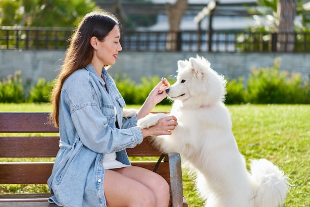 Photo chien samoyède avec sa femme propriétaire au parc jouant ensemble