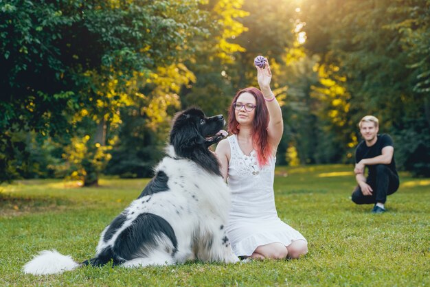 Chien Terre-Neuve joue avec l'homme et la femme dans le parc