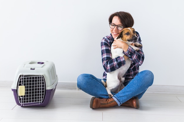 Chien transportant des sacs et des animaux de compagnie propriétaire concept - jolie femme joyeuse en chemise à carreaux détient favori