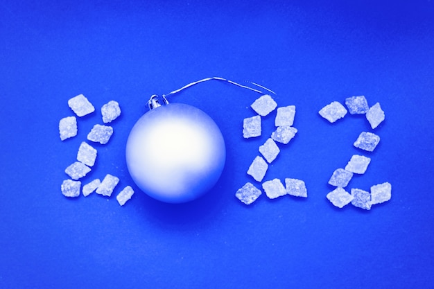 Chiffre 2022 de bonbons et boule de Noël sur fond bleu