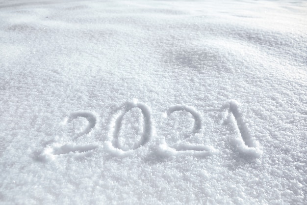 Chiffres, date du calendrier, inscription 2021 sur une surface enneigée naturelle en hiver