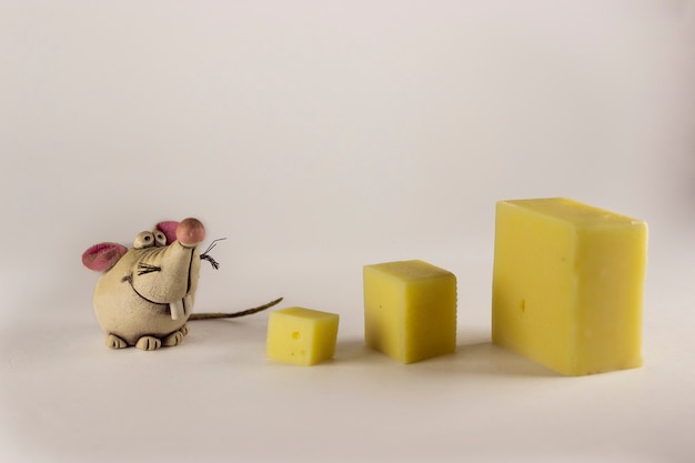 Chiffres De Rats Et Un Morceau De Fromage Sur Fond Blanc. Statuette de souris, gros plan. Notion de nouvel an. Mise au point sélective.