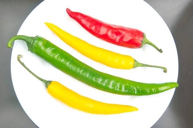 Chili chaud jaune, rouge et vert sur une assiette. Poivre. Nourriture vitaminée végétale.