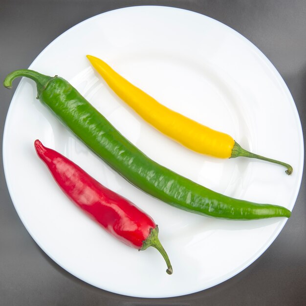 Chili chaud jaune, rouge et vert sur une assiette. Poivre.