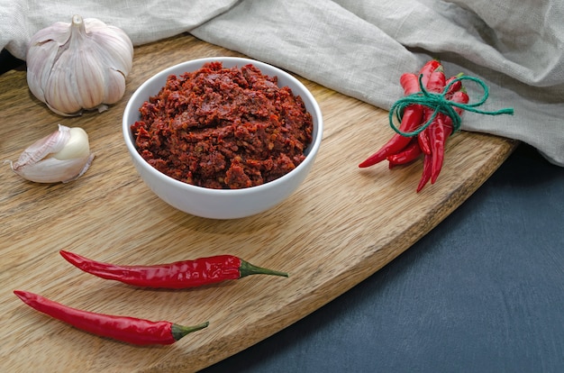 Chili épicé sur une table sombre dans des assiettes en céramique sur une planche de bois, flatlay. Utilisé comme ingrédient pour harissa, ajika, muhammara. Cuisine orientale et moyen-orientale.