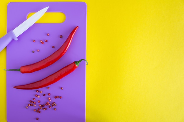 Chili poivré sur la planche à découper violette sur fond jaune