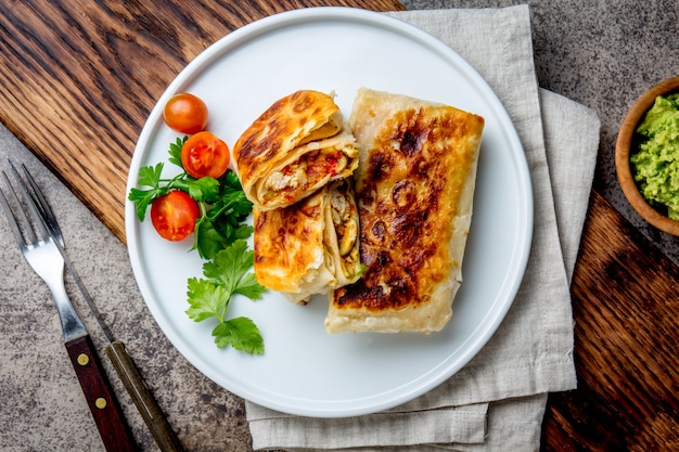 Chimichanga mexicain sur une plaque blanche servie avec du guacamole