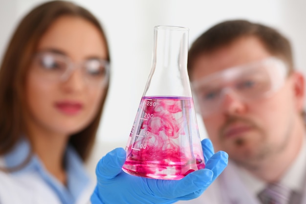 Une chimiste tient un tube à essai de verre dans sa main qui déborde d'un liquide
